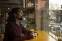 Задумчивый человек смотрит в окно в кафе — стоковое фото