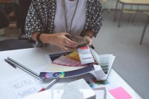 Femmina dirigente controllo colore swatch sul tavolo da disegno in ufficio — Foto stock