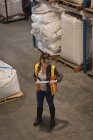 Женщина-работница проверяет время во время использования цифрового планшета на складе — стоковое фото