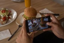 Крупный план женщины, фотографирующей еду в кафе — стоковое фото