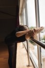 Ballerina stretching on barre while practicing ballet dance in dance studio — Stock Photo