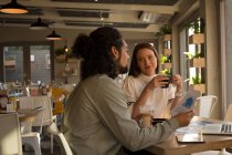Führungskräfte diskutieren im Café über Dokumentenpapier — Stockfoto
