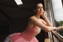 Ballerine réfléchie regardant par la fenêtre dans le studio de danse — Photo de stock