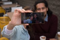 Primer plano de la pareja tomando selfie en la cafetería al aire libre - foto de stock