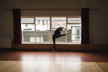 Балерина практикует балет у окна в танцевальной студии — стоковое фото