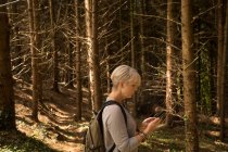 Seitenansicht einer Frau mit Handy im Wald — Stockfoto