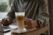 Partie médiane de l'homme tenant une tasse de café dans un café — Photo de stock
