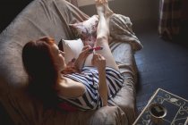 Mujer usando lima de uñas en el sofá en casa - foto de stock