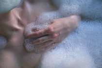 Seção média da mulher relaxando na banheira no banheiro — Fotografia de Stock
