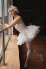 Продумана балерина дивиться крізь вікно в танцювальній студії — стокове фото