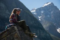 Romantisches Paar sitzt auf einem Felsen in der Nähe des Berges — Stockfoto