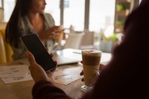 Крупный план человека с помощью мобильного телефона в кафе — стоковое фото