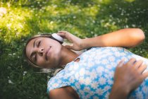 Woman listening music in garden — Stock Photo