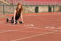Joven atlética haciendo ejercicio en pista de atletismo - foto de stock