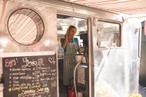 Serveur féminin préparant le café dans le camion de nourriture — Photo de stock