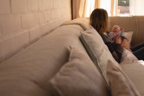 Madre acunando a su bebé en el sofá en casa - foto de stock