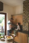 Padre e hija interactuando mientras lavan vegetales en la cocina en casa - foto de stock