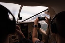Piloto tira fotos com celular enquanto voa no cockpit da aeronave — Fotografia de Stock