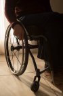 Sección media del hombre discapacitado en silla de ruedas en casa - foto de stock