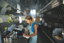 Woman waitress writing orders on notepad in food truck — Stock Photo