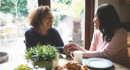 Mother and daughter consoling each other on dinning table at home — Stock Photo