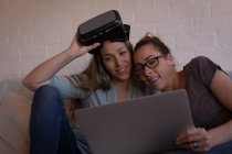 Couple lesbien utilisant un ordinateur portable sur un canapé à la maison — Photo de stock