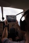 Пилот фотографируется с цифровым столом во время полета в кабине самолета — стоковое фото