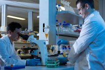 Scientifiques masculins expérimentant ensemble en laboratoire — Photo de stock