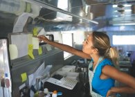 Mulher garçonete olhando para ordens em notas pegajosas no caminhão de alimentos — Fotografia de Stock
