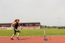 Junge Leichtathletin überwindet Hürde auf Sportbahn — Stockfoto