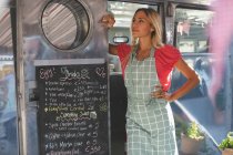 Garçonete feminina pensativa em pé no caminhão de alimentos — Fotografia de Stock
