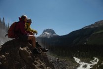 Pareja relajándose en una roca en las montañas - foto de stock
