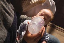 Close-up of mother feeding with milk bottle to baby at home — Stock Photo