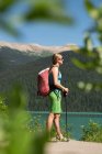 Wanderin steht am Flussufer in den Bergen — Stockfoto