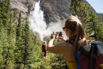 Caminhante feminino clicando fotos com telefone celular em montanhas — Fotografia de Stock