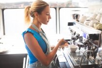 Woman waitress preparing coffee in food truck — Stock Photo