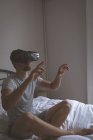Hombre usando auriculares de realidad virtual en el dormitorio en casa - foto de stock