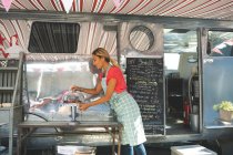 Вид сбоку на официантку, работающую возле фургона с едой — стоковое фото
