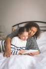 Grandmother and granddaughter using digital tablet in bedroom at home — Stock Photo