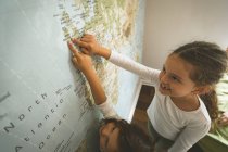 Siblings pointing towards map at home — Stock Photo