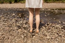 Low section of woman standing near stream at countryside — Stock Photo