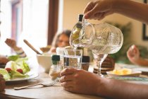 Close-up of man serving water in glass on dining table at hom — Stock Photo