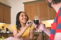 Romántica pareja tostando copas de vino en casa - foto de stock