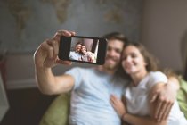 Pareja tomando selfie con teléfono móvil en casa - foto de stock