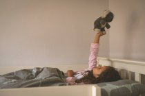 Девушка играет с плюшевым мишкой на кровати дома — стоковое фото