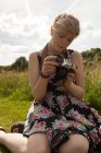 Женщина рассматривает фотографии на камеру в поле — стоковое фото