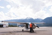 Ingénieur entretien moteur d'avion près du hangar par une journée ensoleillée — Photo de stock