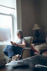 Mulher sênior usando telefone celular na sala de estar em casa — Fotografia de Stock