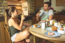 Casal tomando café da manhã e suco na mesa de jantar em casa — Fotografia de Stock