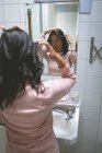 Жінка стоїть з рукою на волоссі у ванній вдома — стокове фото